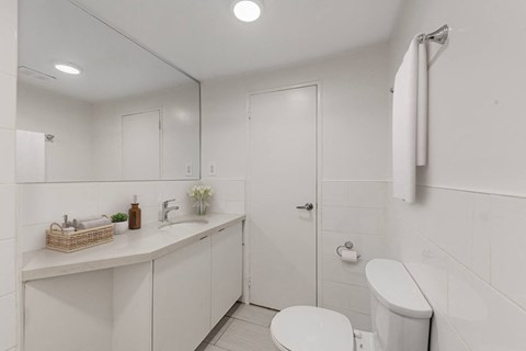 A white bathroom with a toilet, sink, and mirror.
