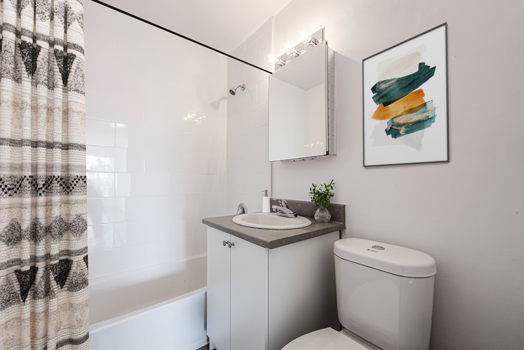 A bathroom with a toilet, sink, and a painting on the wall.