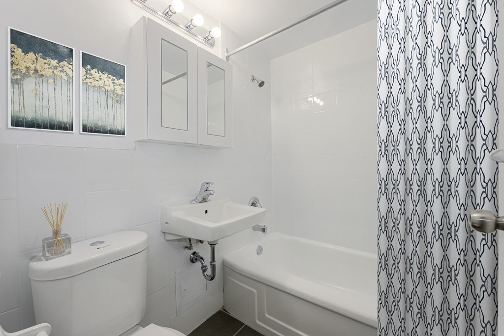 A white bathroom with a toilet, sink, and bathtub.
