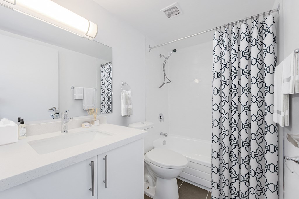 A white bathroom with a patterned shower curtain.