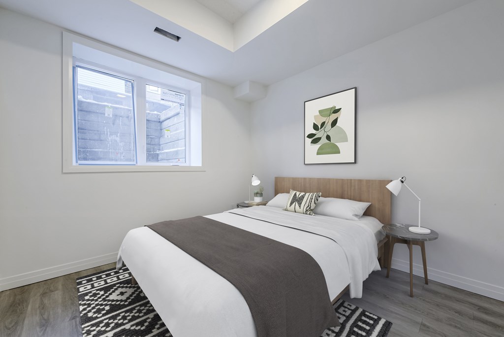 A bedroom with a bed, nightstand, and a framed picture on the wall.