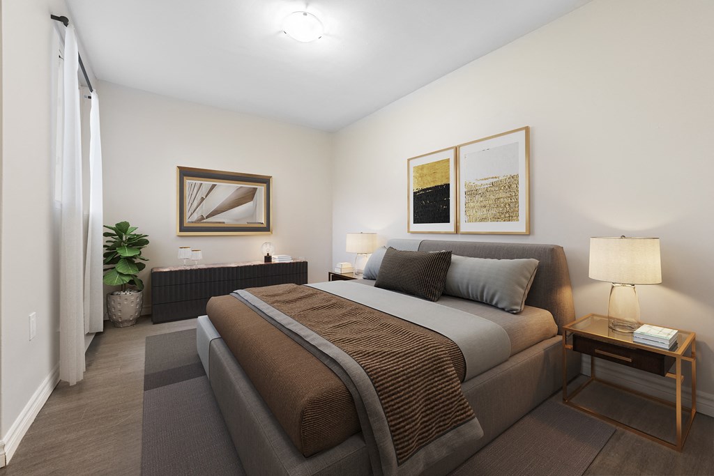 A bedroom with a large bed and a small table with a lamp on it.