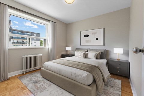 A bedroom with a large bed, two nightstands, and a window with a view of a building outside.