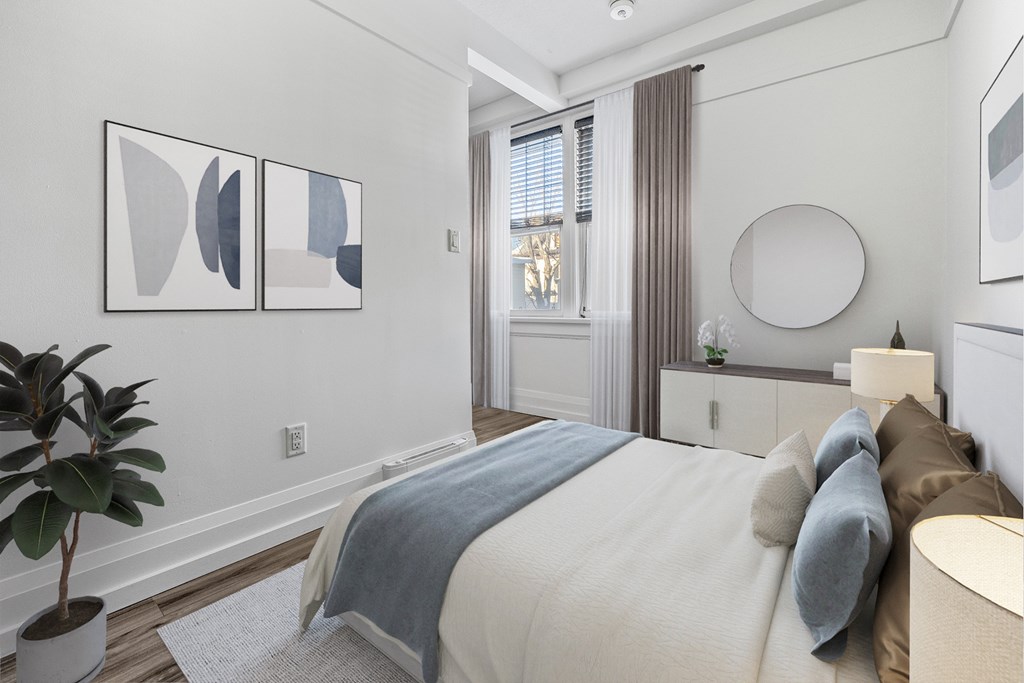 A bedroom with a bed, pillows, and a plant.