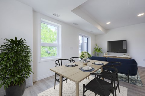 A dining room with a table set for two and a couch in the background.