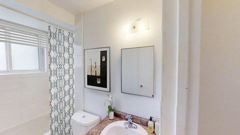 A bathroom with a toilet, sink, and a mirror.