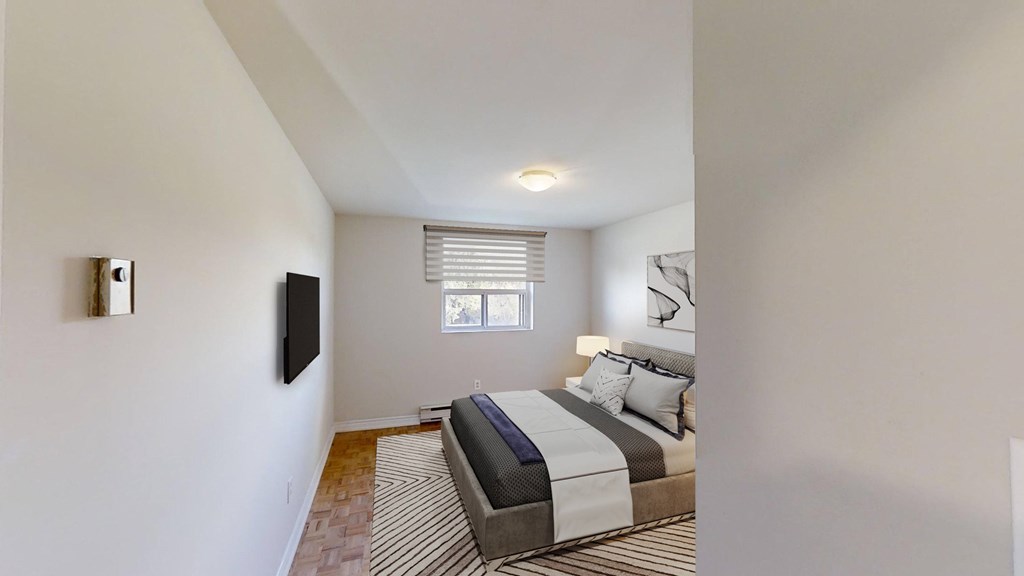 A bedroom with a bed, a television, and a window.