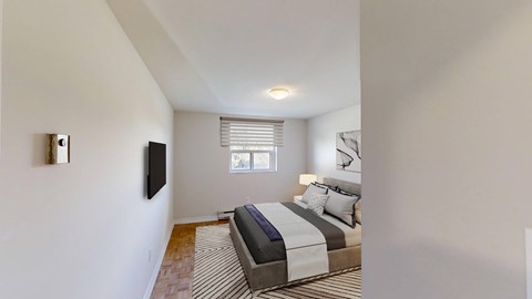 A bedroom with a bed, a television, and a window.