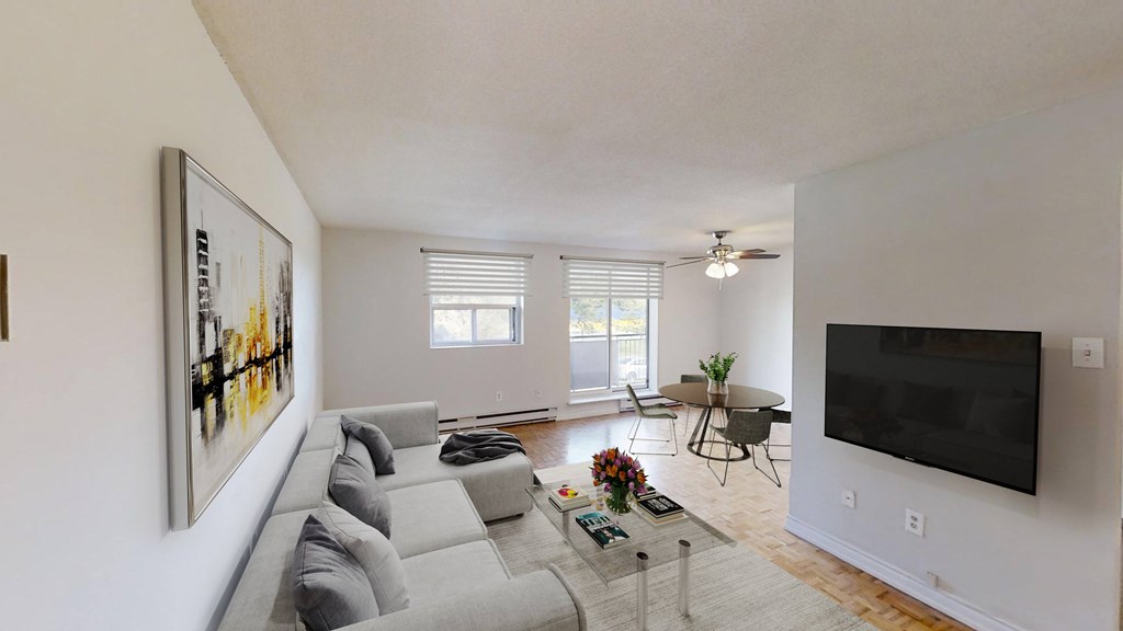 A living room with a grey couch and a painting on the wall.