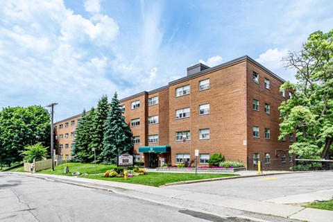 A large brick building with a green awning sits on a street corner.