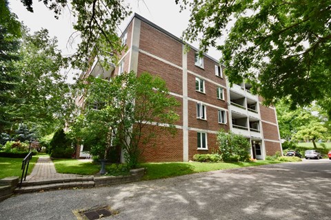 A red brick building with a tree in front.