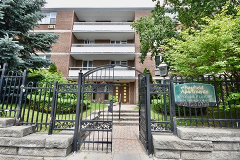 The image shows the entrance to Bayfield Apartments with a sign that reads "Affordable Luxury."