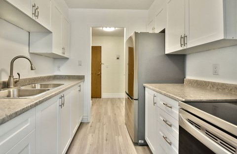 A kitchen with white cabinets and a wooden floor.