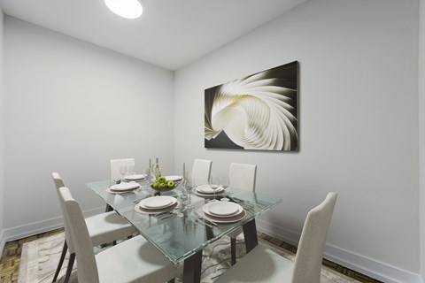 A dining room with a glass table and chairs and a painting on the wall.