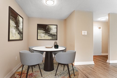 A dining room with a round table and grey chairs.