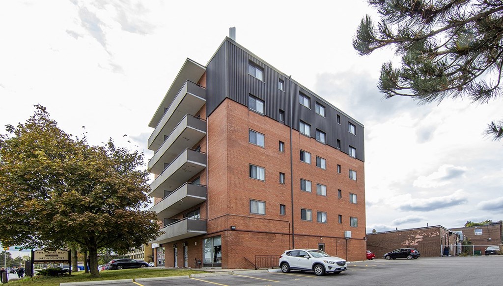 A modern apartment building with a white car parked in front.