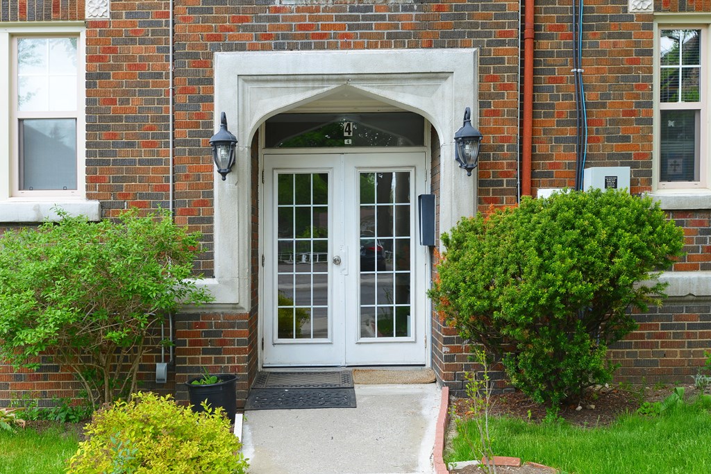 A white door with a glass window is flanked by two black lanterns.