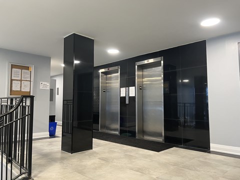 A hallway with a black and white color scheme and a blue trash can.