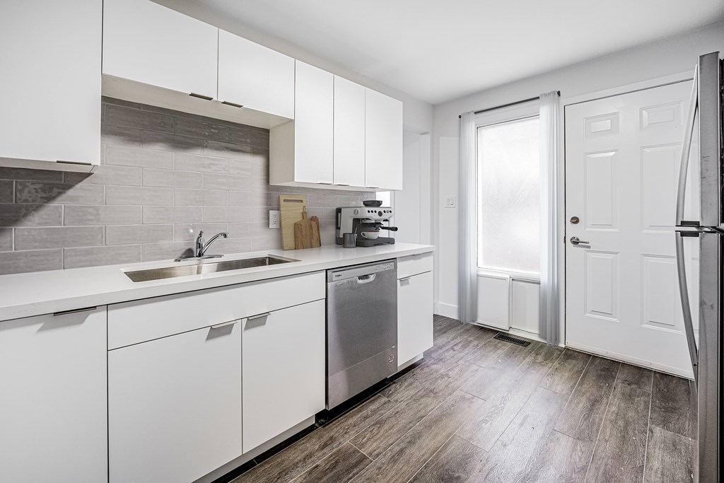 A kitchen with white cabinets and a wooden floor.
