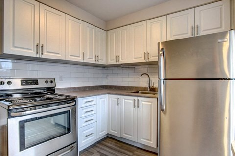 A kitchen with white cabinets and a stainless steel refrigerator.