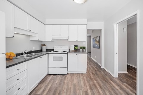A kitchen with white cabinets and a wooden floor.
