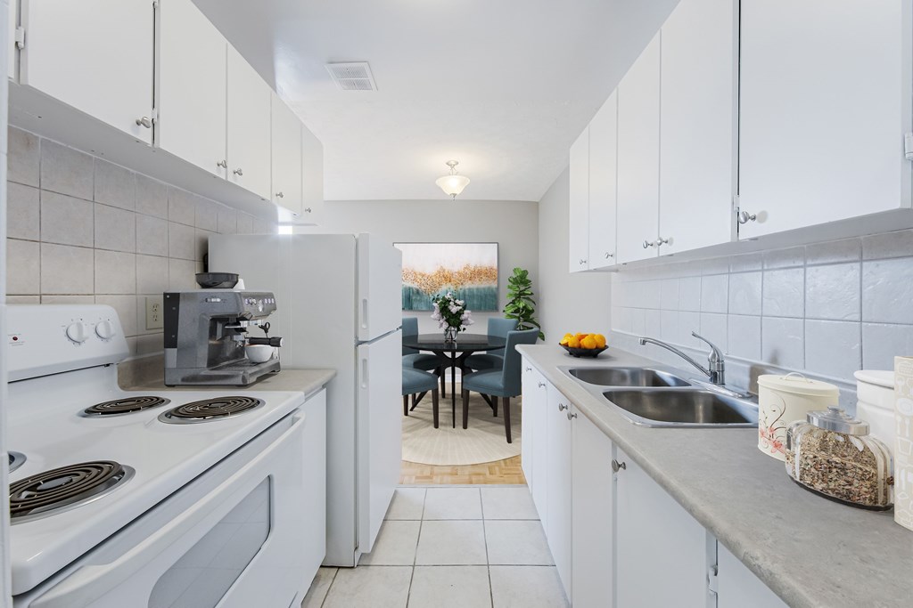 A kitchen with white cabinets and a stove top oven.