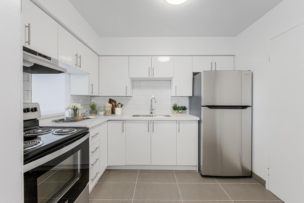 A modern kitchen with white cabinets and a stainless steel refrigerator.