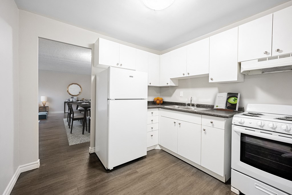 A white kitchen with a refrigerator, oven, and cabinets.