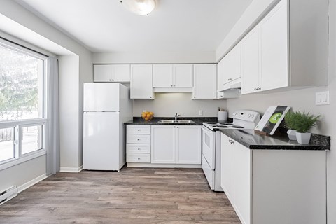 A kitchen with white cabinets and a black countertop.