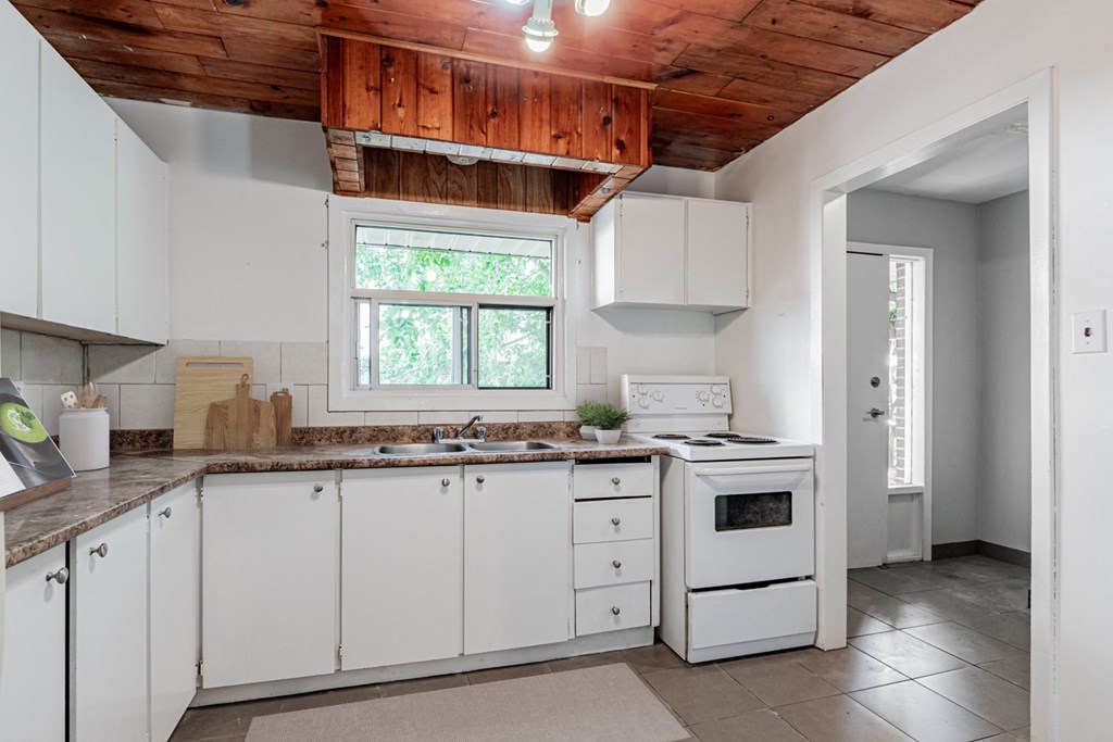 A kitchen with white cabinets and a wooden ceiling.