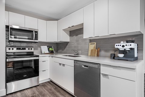A modern kitchen with white cabinets and stainless steel appliances.