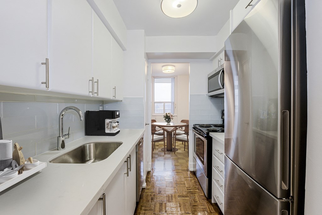 A kitchen with white cabinets and a stainless steel refrigerator.