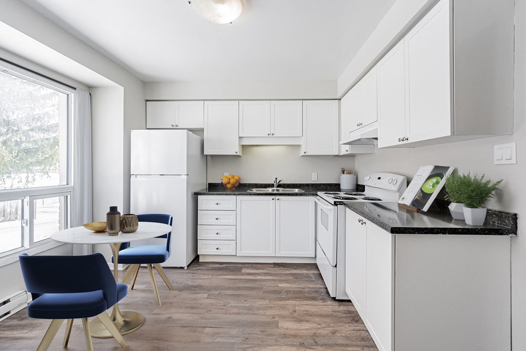 A kitchen with white cabinets and a black countertop.