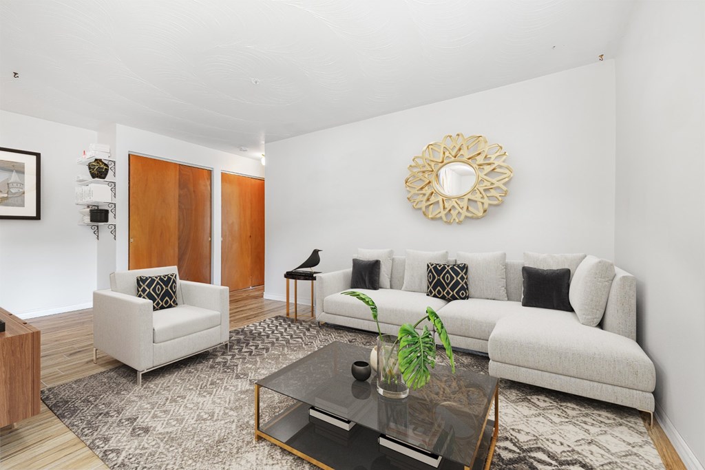 A living room with a white couch, a coffee table, and a mirror on the wall.