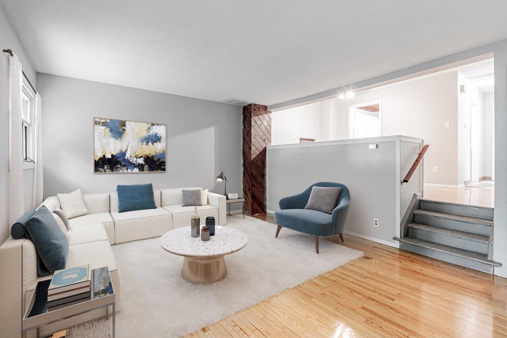 A living room with a white couch, a blue armchair, and a coffee table.