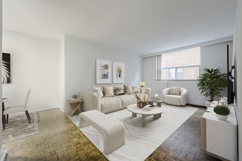 A living room with a white couch, a coffee table, and a television.
