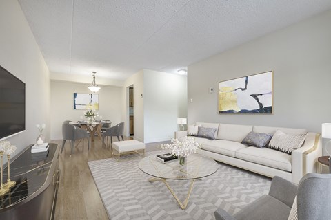 A modern living room with a white sofa, grey chairs, and a glass coffee table.