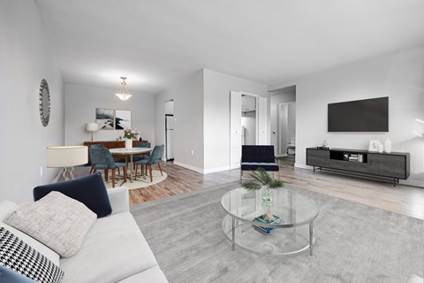 A modern living room with a glass coffee table and a white sofa.