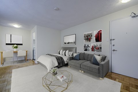 A bedroom with a bed, couch, and pictures on the wall.