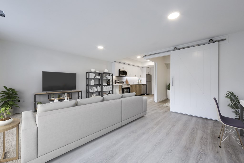 A modern living room with a white couch and a television on the wall.