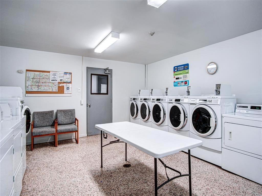 A laundry room with a table, chairs, and washing machines.