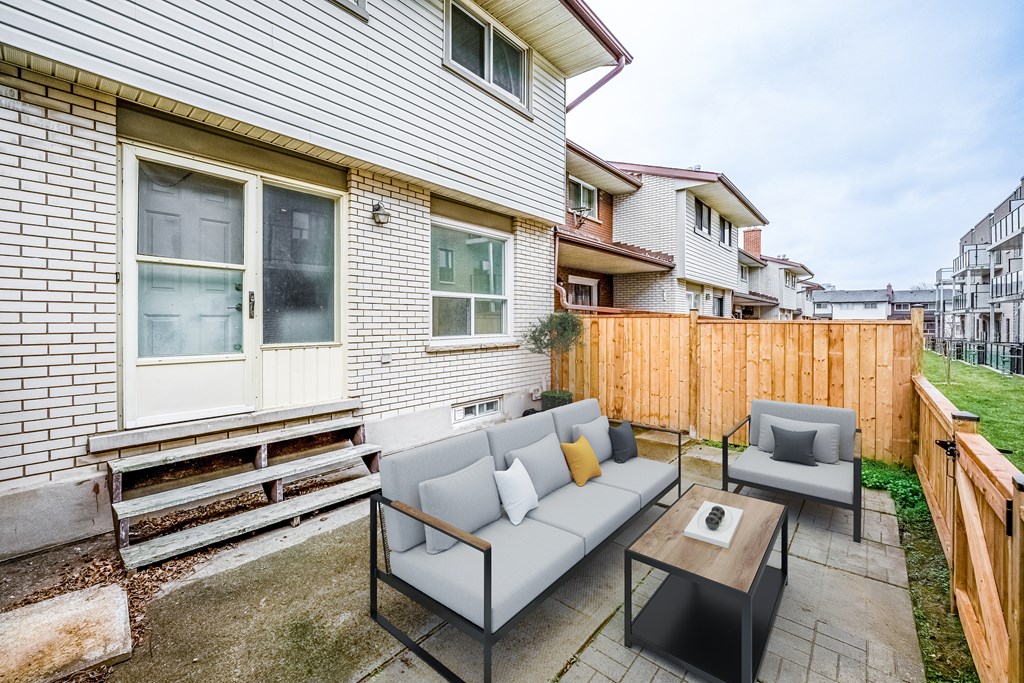 A patio with a grey couch and a coffee table.