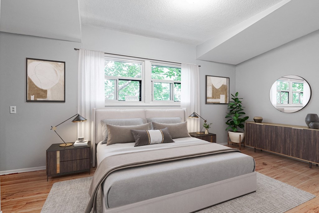 A bedroom with a large bed, a side table with a lamp, and a potted plant.