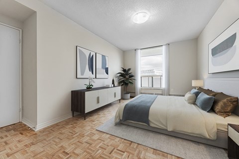 A bedroom with a bed, nightstand, and a plant.