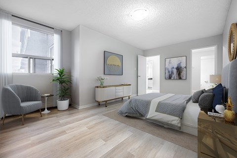 A well-lit bedroom with a large bed and a chair by the window.