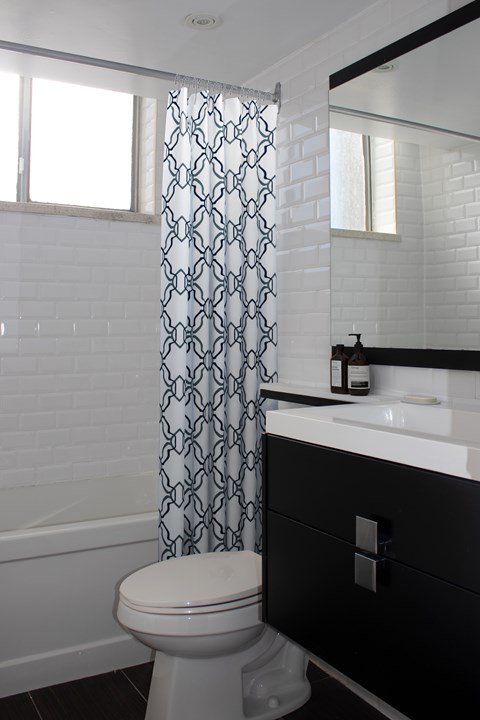 A white toilet in a bathroom with a black and white cabinet.