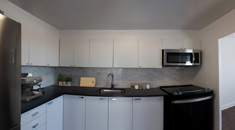 A kitchen with white cabinets and a black dishwasher.
