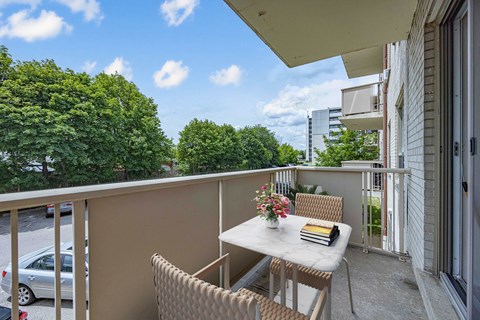 A balcony with a table and chairs overlooking a parking lot.
