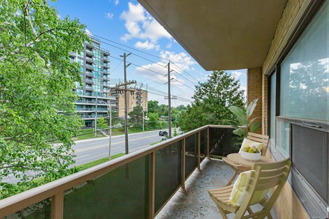 A balcony with two chairs and a table overlooking a street.