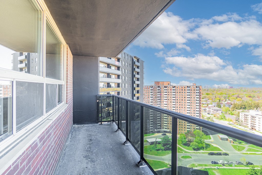A balcony with a view of a green field and buildings.